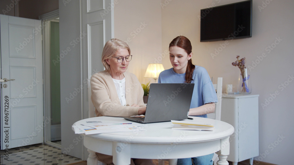 A woman from social services comes to visit an elderly lady. The girl helps the pensioner deal with the laptop A woman from social services comes to visit an elderly lady. The girl helps the pensioner deal with the laptop