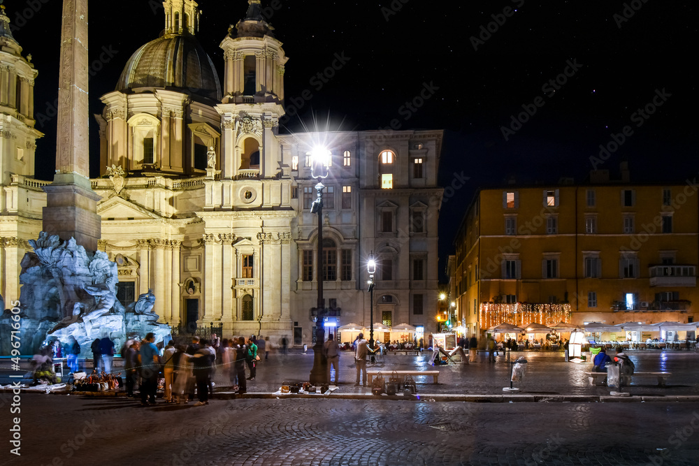 Night view of Piazza Navona with illuminated cafes, the Sant'Agnese in Agone Church and Fountain of the Four Rivers in Rome, Italy. 