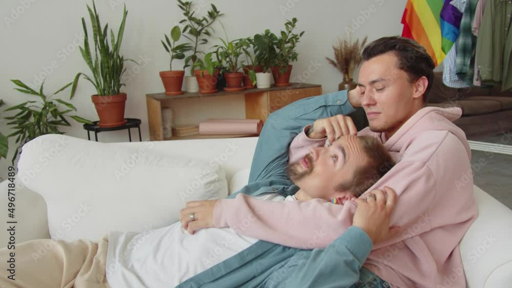 Two lgbt men are lying on the sofa, looking at each other and stroking hair Two lgbt men are lying on the sofa, looking at each other and stroking hair