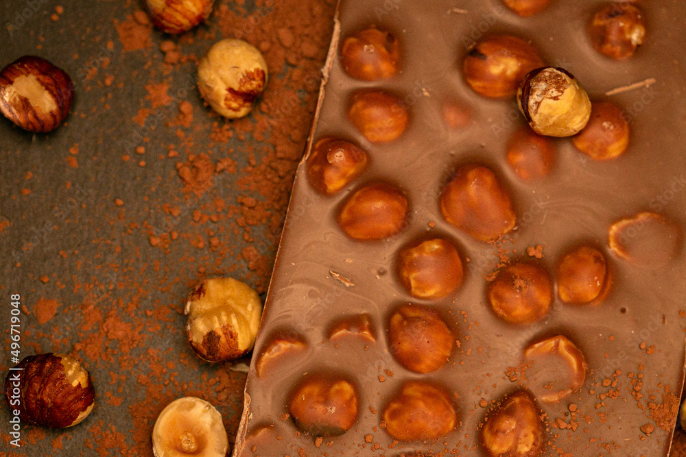 Chocolate with hazelnuts and cocoa powder on a black slate background.Chocolate dessert with nuts.Bar of chocolate on a dark background.Desserts and sweets.Chocolate bar. Chocolate with hazelnuts and cocoa powder on a black slate background.Chocolate dessert with nuts.Bar of chocolate on a dark background.Desserts and sweets.Chocolate bar.