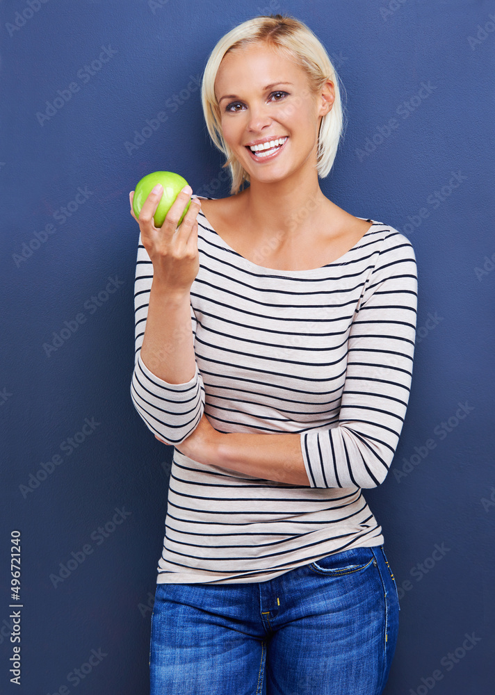 Snacking with a smile. Studio shot of an attractive young woman holding an apple. Snacking with a smile. Studio shot of an attractive young woman holding an apple.
