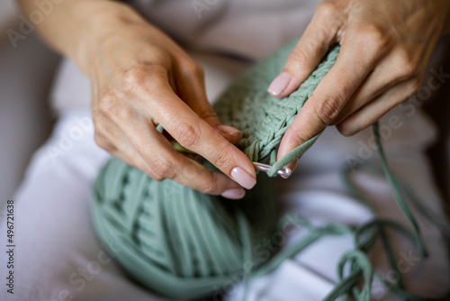 Foto Closeup female hands knitting interior decor basket use green ribbon yarn and cr