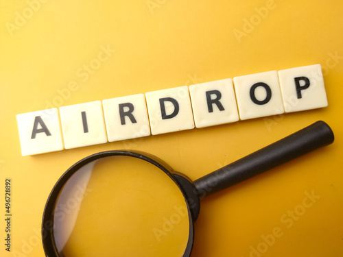 Magnifying glass and toys word with text AIRDROP on yellow background. photo