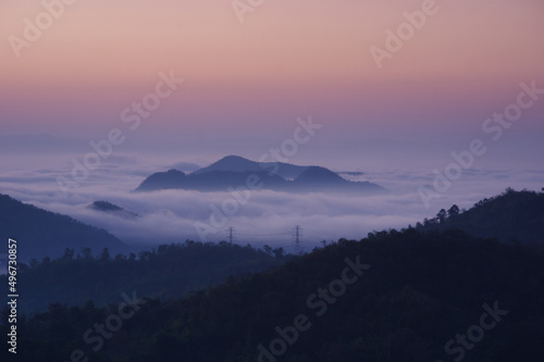 Aerial view Transmission tower in green forest and beautiful morning smooth fog. Energy and environment concept. High voltage power poles. Pang Puay, Mae Moh, Lampang, Thailand.