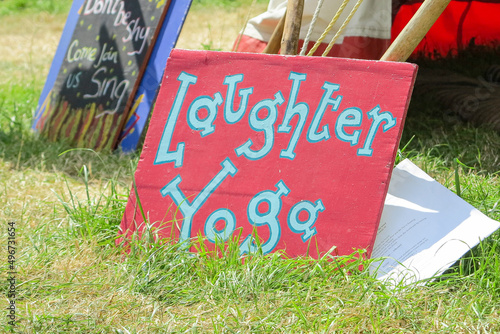 Glastonbury, England - A sign advertising Laughter and Yoga leaning against a tent in The Healing Fields at Glastonbury Festival 2019.