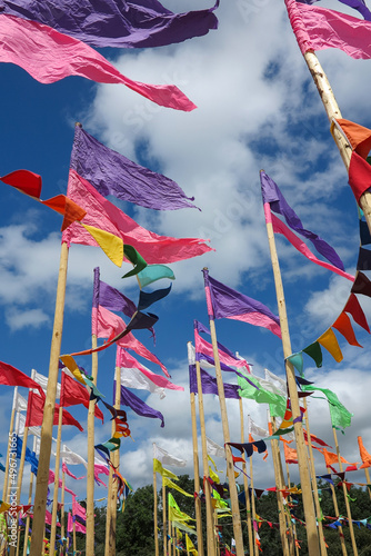 Glastonbury, England - Bright, rainbow-coloured flags waving against a blue sky with clouds at Glastonbury Music Festival 2019.  Image has copy space.