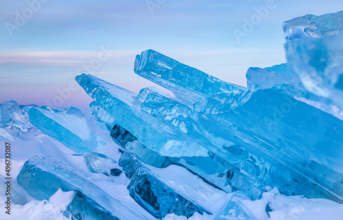 Beautiful transparent blue ice blocks, sunset sky in the background, cracked ice, frozen, Baikal lake, ice hummock
