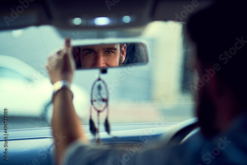 I am ready for the day. Rearview shot of a unrecognizable man driving in his car while looking into the rearview mirror. © Ruan J/peopleimages.com