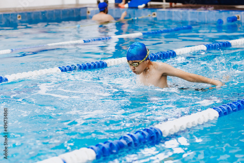 latin child boy swimmer wearing cap and goggles in a swimming training holding On Starting Block In the Pool in Mexico Latin America	