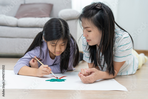 Mother teaches child to paint and paint in the living room. Good times together of single moms. Learn the arts and be together for a happy time.