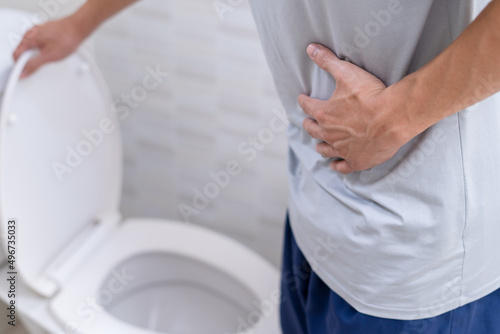 man standing has diarrhea and severely toxic food. Man touch belly in the bathroom. Abdominal pain, Diarrhea, Colon cancer concept