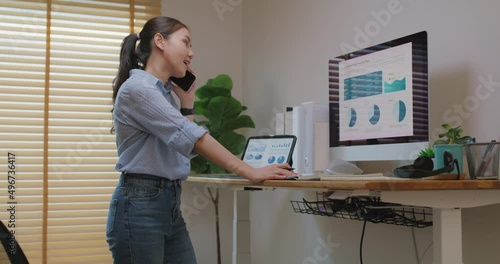 Electric adjustable standing desk in small office workspace for PC desktop computer worker. Asia people young woman relax remote work at home proper height up workstation physical workforce challenge. photo