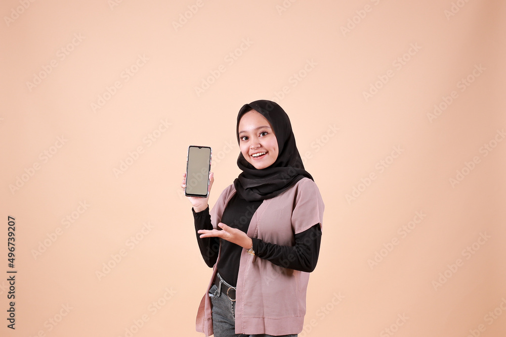 Young beautiful asian woman holding blank white screen smart phone on orange background. Indonesia women Young beautiful asian woman holding blank white screen smart phone on orange background. Indonesia women