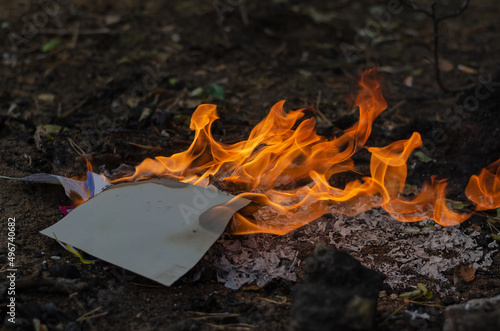 Burning in the fire of a torn notebook. The cover and the multi-colored sheets burn into gray ash. photo