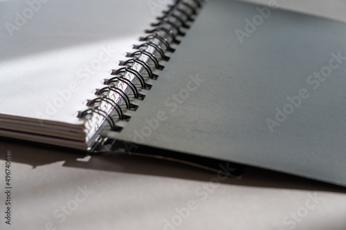 Black spring-loaded notebook against a gray background. Close-up of an open notebook and blank white sheets.