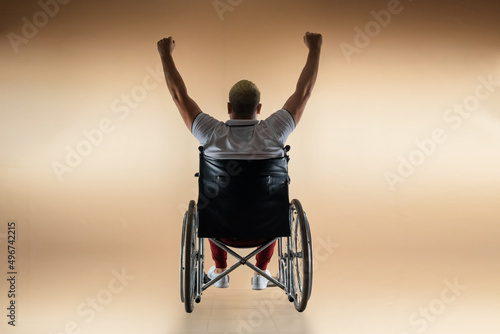 Silhouette of a disabled man in a wheelchair raised his hands. The concept of disability and illness, happiness, joy, success.