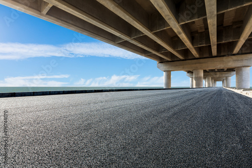 Asphalt road and bridge with river under blue sky