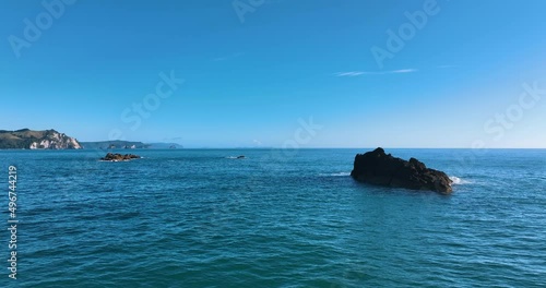 Flight around rocky reef over turquoise sea at Whiritoa Beach - New Zealand photo