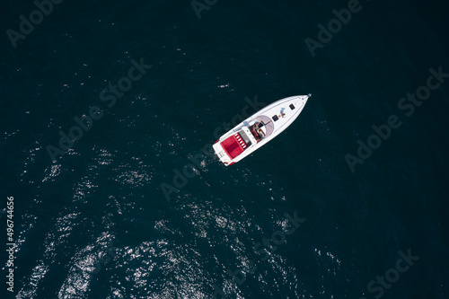 Parking white boat on the water drone view. Speedboat parking on the water top view. Speed boat with red seats aerial view. People rest on a boat.