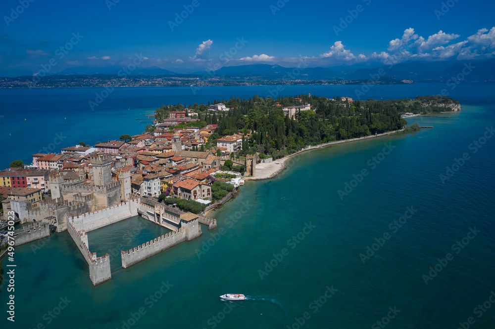 Aerial view on Sirmione sul Garda. Italy, Lombardy. Rocca Scaligera Castle in Sirmione. Boat with tourists near the main castle. View by Drone.