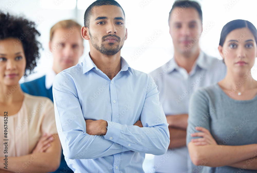 Leadership is action not position. Portrait of a handsome young business man with his colleagues in the background. Leadership is action not position. Portrait of a handsome young business man with his colleagues in the background.