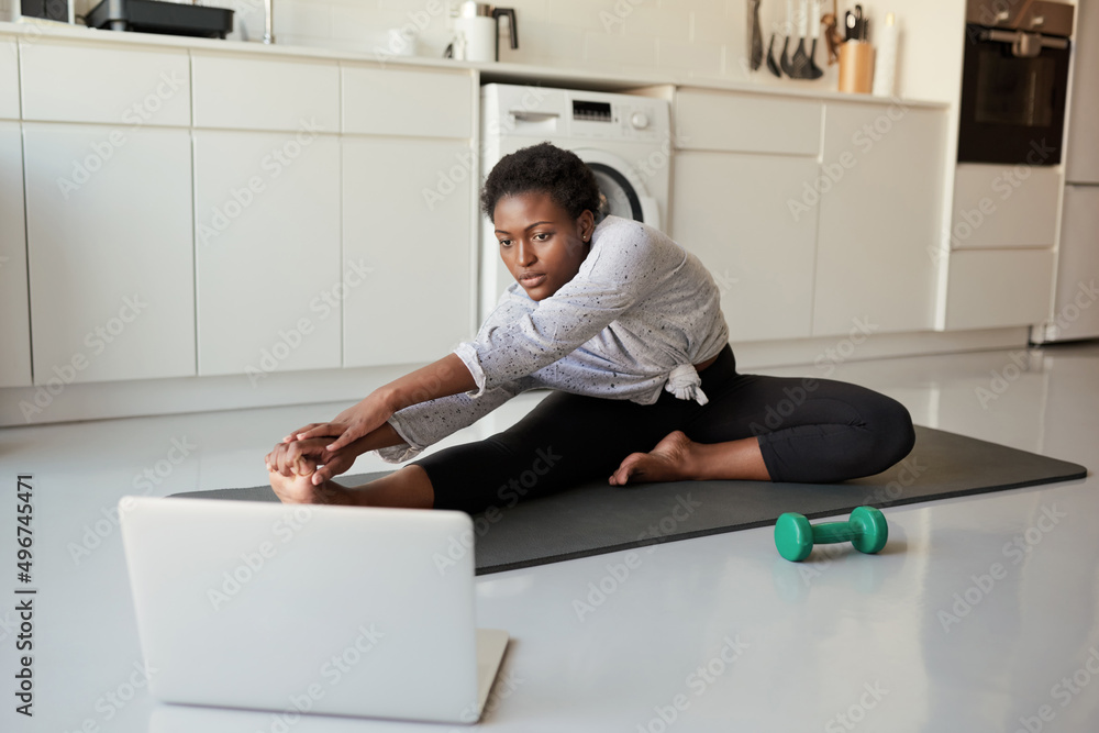 Online training is really growing in popularity. Shot of a young woman using a laptop while exercising at home. Online training is really growing in popularity. Shot of a young woman using a laptop while exercising at home.