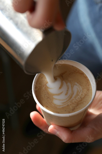 Barista prepares coffee in a paper cup