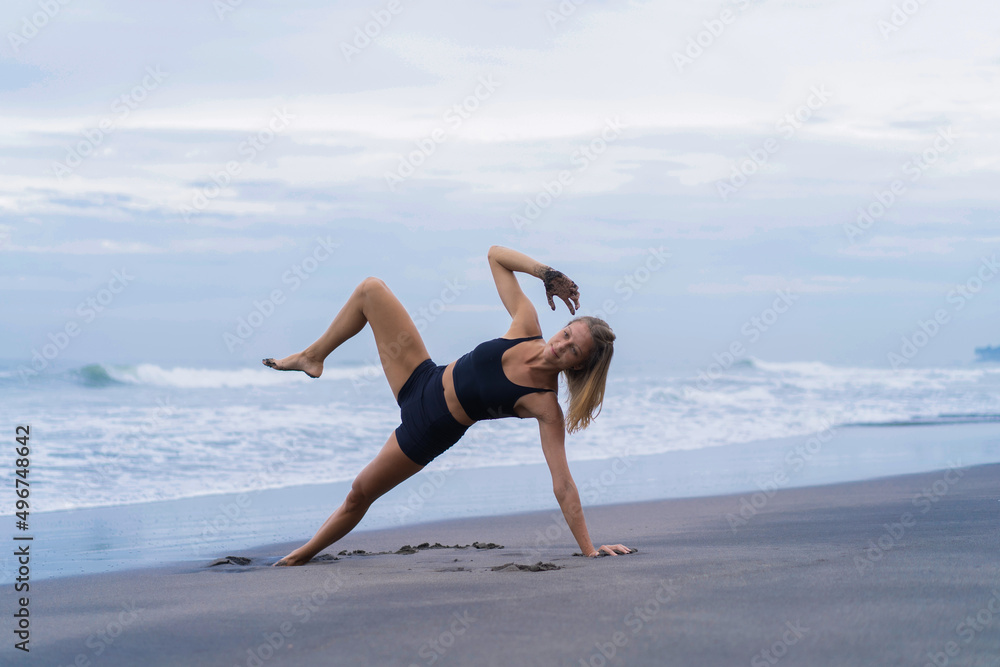 Sporty woman doing mountain climber exercise - run in plank to burn fat. Sunset beach, blue sky background. Healthy lifestyle at tropical island yoga retreat, outdoor activity, family summer vacation.