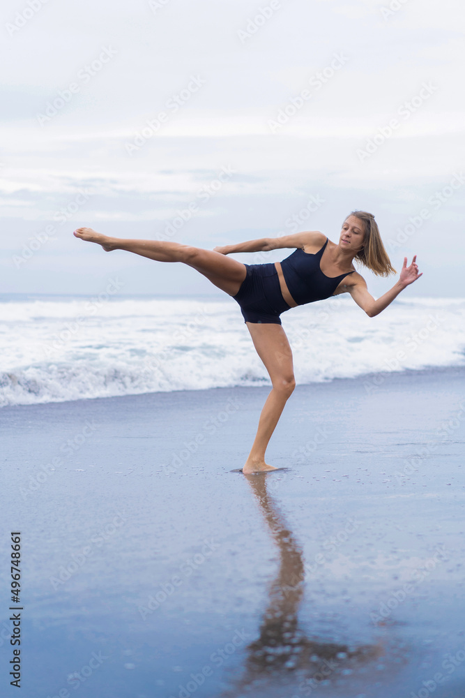 Young woman trains on the beach, taekwondo, kicks, spinner, roundhouse kick.