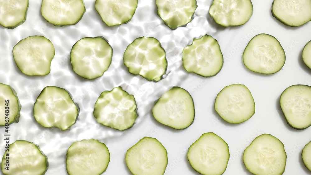 Top view shot of single wave making ripples on water surface over cucumber slices arranged in rows on white background | beauty background, face lotion commercial Top view shot of single wave making ripples on water surface over cucumber slices arranged in rows on white background | beauty background, face lotion commercial