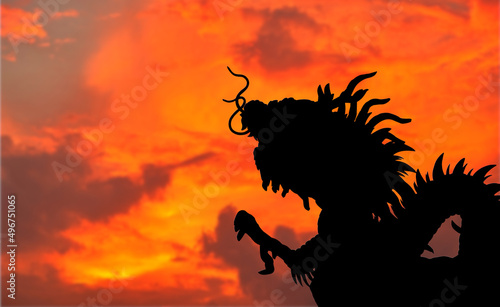 Close-up silhouette dragon statue from roof top of Chinese Temple on sunset sky background with copy space, The dragon is a sacred animal that the Chinese respect and worship.