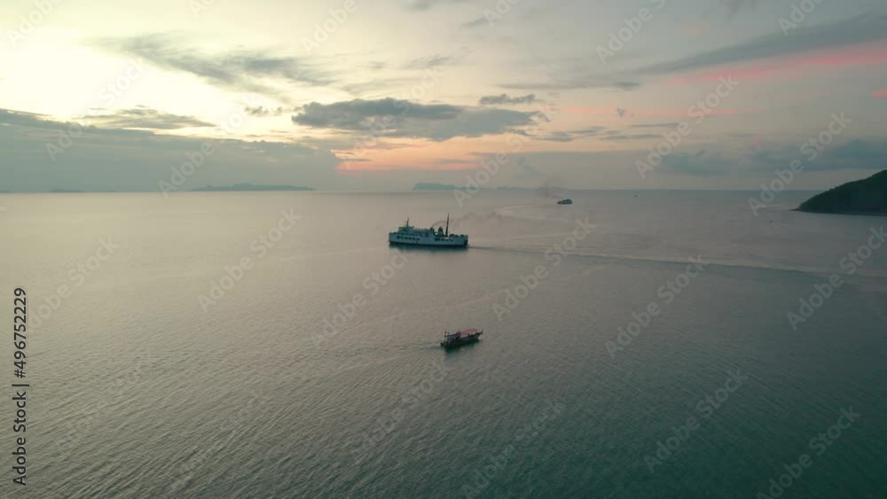 Ferry and small fishing boat sailing in high sea in Koh Samui, Thailand with a beautiful sunset in the background Ferry and small fishing boat sailing in high sea in Koh Samui, Thailand with a beautiful sunset in the background