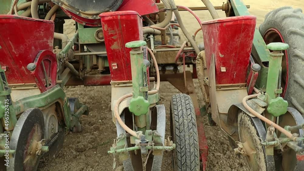 Seed sowing hydraulic seed machine mounted on red tractor, close up of agricultural farming equipment for seed and land preparation