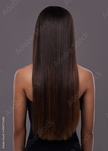 Flawless hair..thanks to her trusty flat iron. Rear view of a young woman with beautiful long hair.
