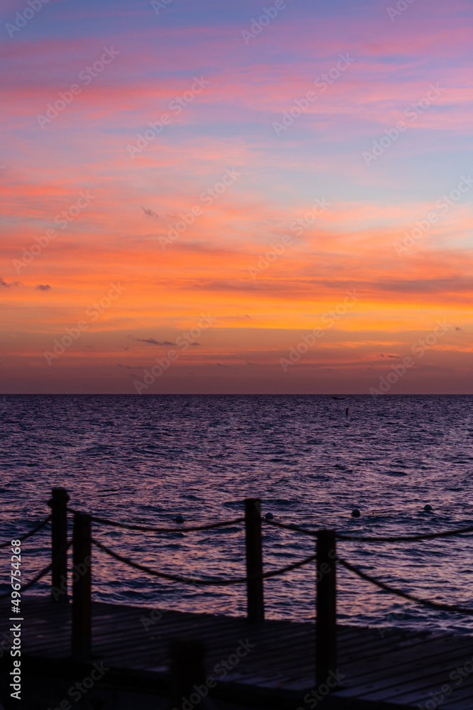 Rope bridge silhouette at sunset. Beautiful seascape, bright orange sky and sea