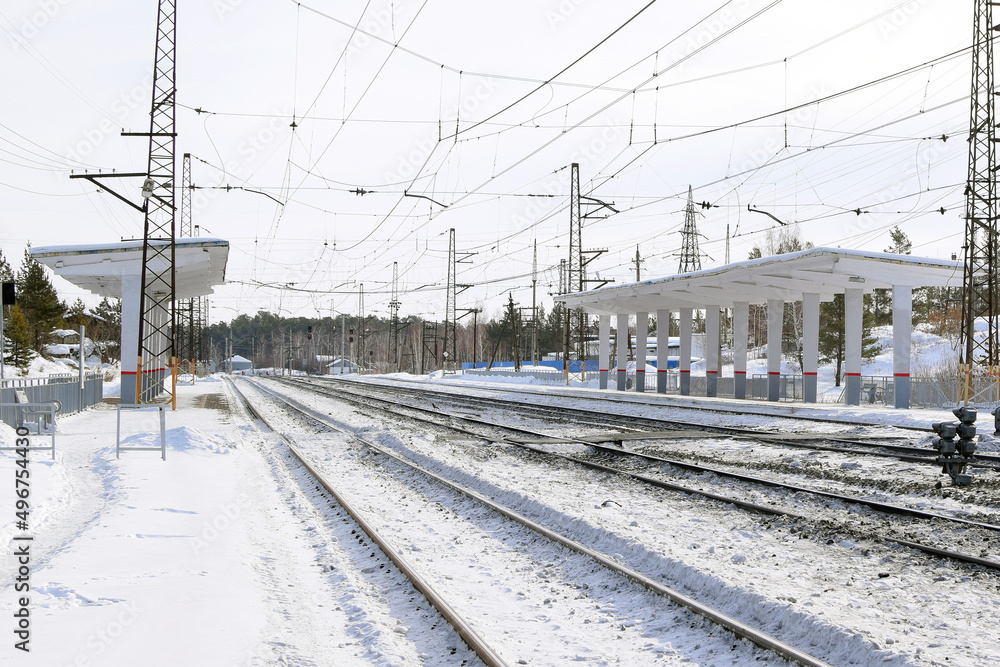 Empty railway track and empty passenger platform, winter landscape.