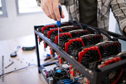Unrecognizable person or an expert building new mining rig for bitcoin cryptocurrency. Blockchain technology and graphic cards in row.