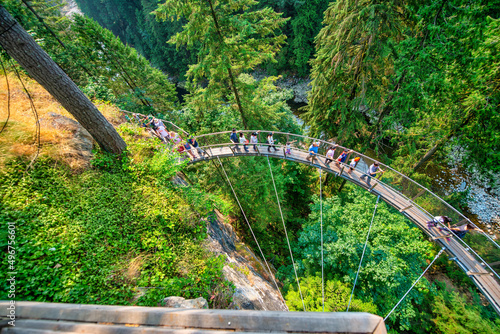 Fototapeta Naklejka Na Ścianę i Meble -  Vancouver, Canada - August 11, 2017: People at Capilano Bridge. It is a Suspension bridge crossing the Capilano River, 140 metres long and 70 metres above the river.