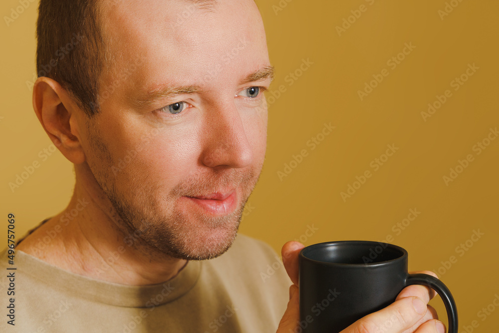 Portrait of a man drinking coffee from a black cup, young european man with black cup Portrait of a man drinking coffee from a black cup, young european man with black cup