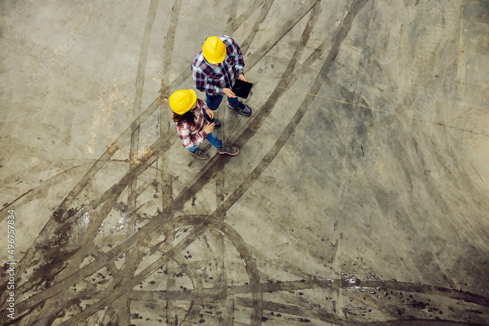 Top view of factory workers walking on muddy floor, using tablet and discussing. Top view of factory workers walking on muddy floor, using tablet and discussing.