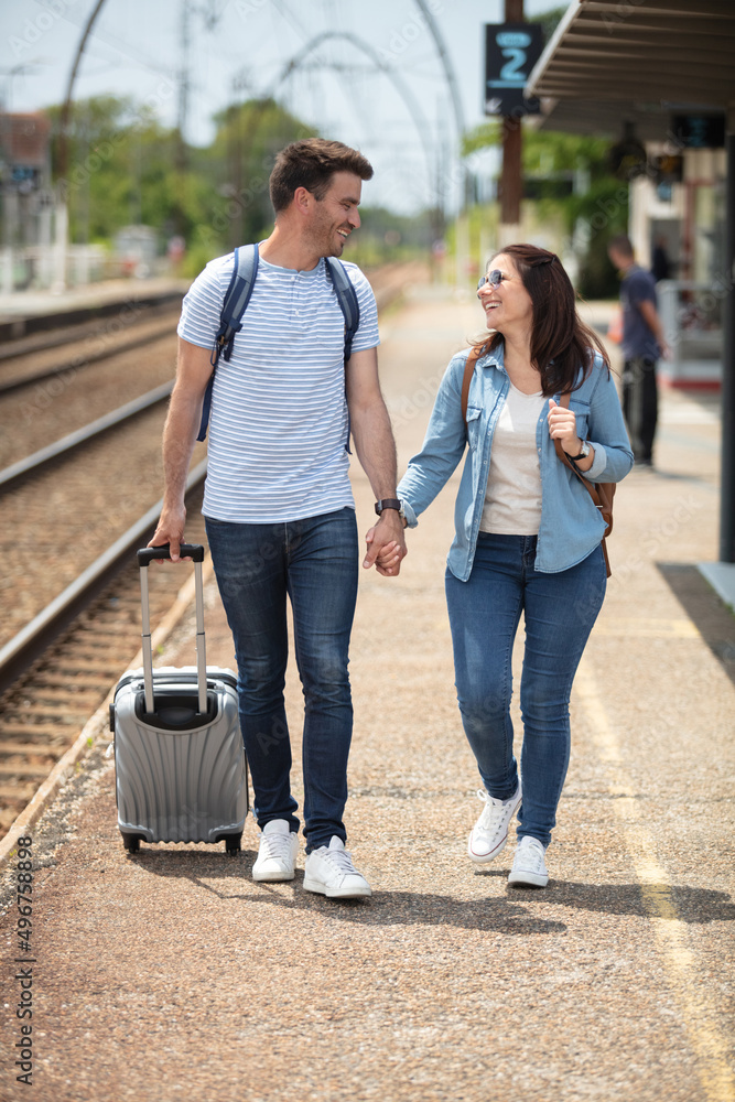 couple on train station pulling trolley luggage couple on train station pulling trolley luggage
