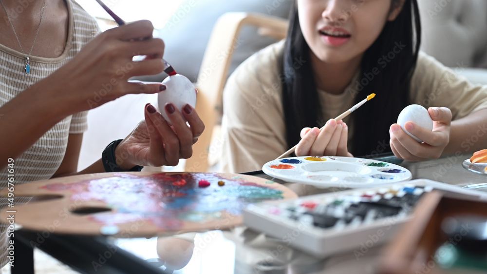 Cropped shot young mother and daughter painting on white eggs preparing for Easter. Cropped shot young mother and daughter painting on white eggs preparing for Easter.