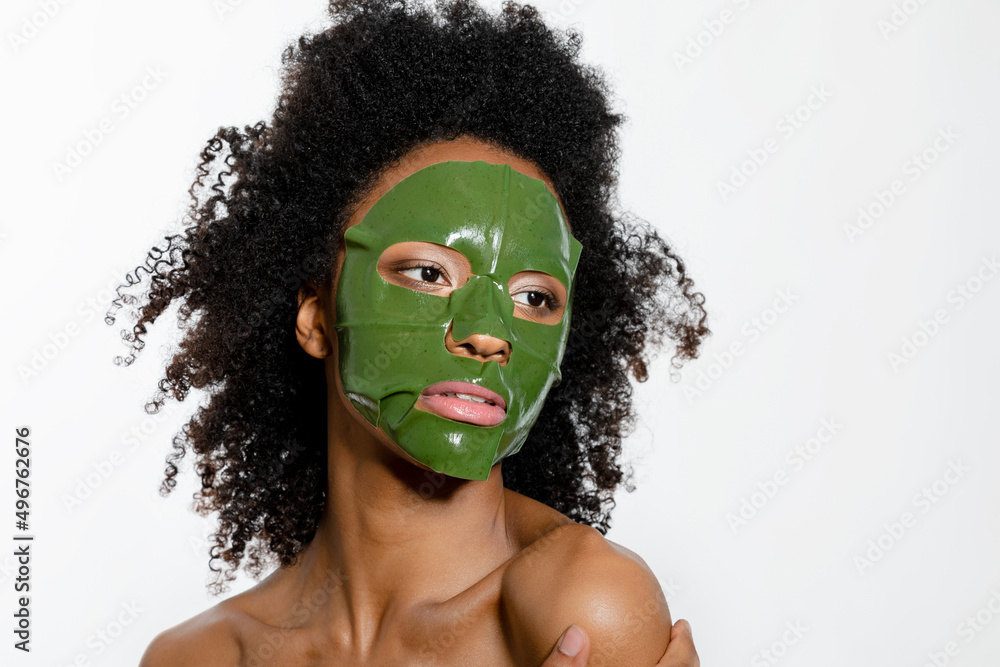 Young woman with facial mask on face against white background Young woman with facial mask on face against white background