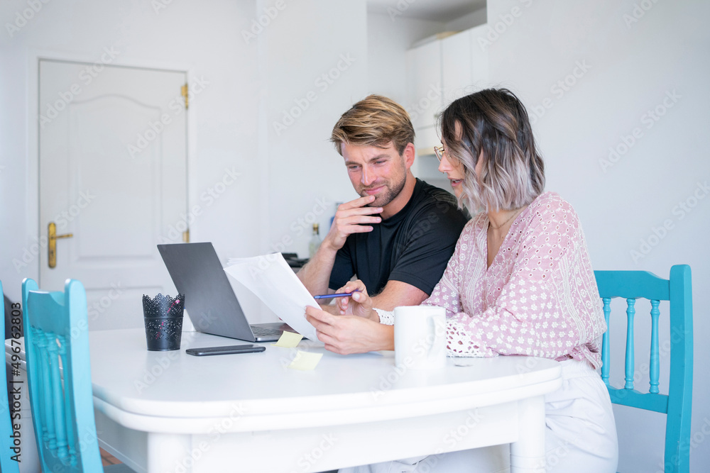 Freelancer discussing over document with woman sitting at dining table Freelancer discussing over document with woman sitting at dining table