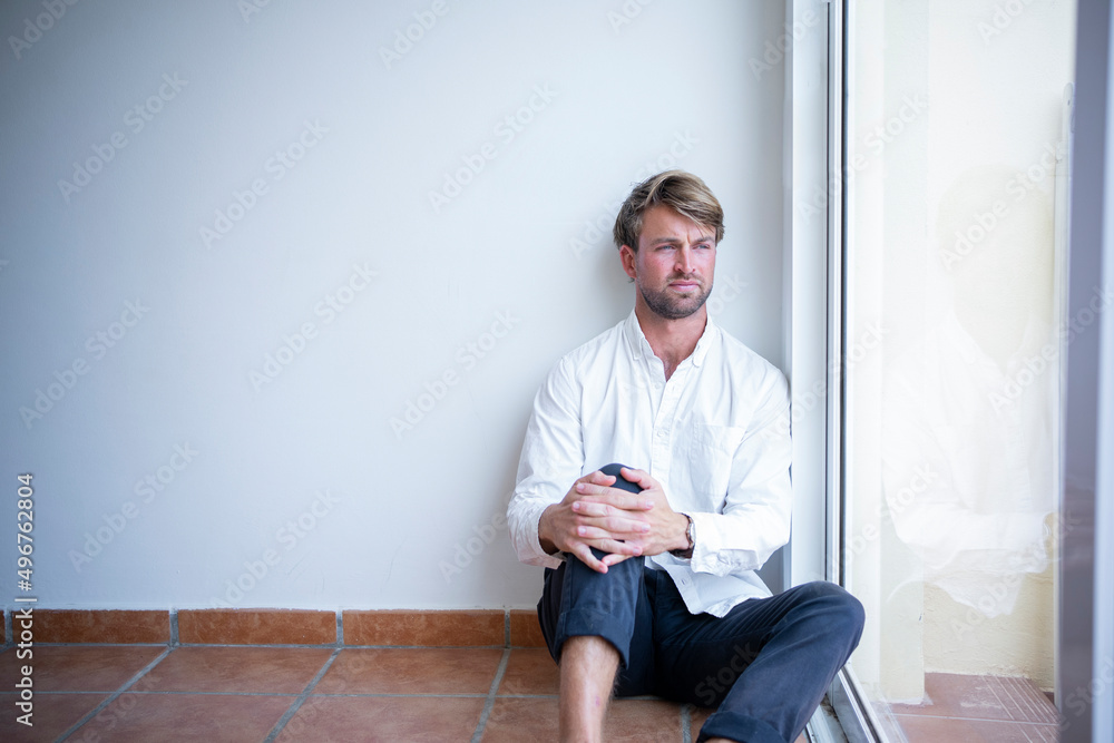 Man looking through glass window sitting at home Man looking through glass window sitting at home