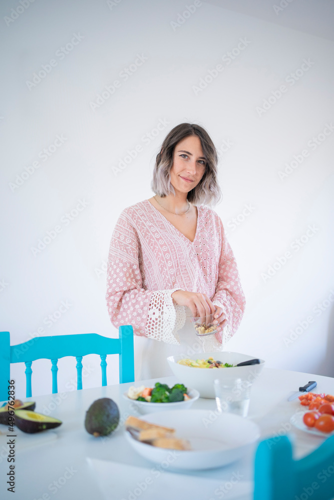 Smiling young woman preparing salad standing at table Smiling young woman preparing salad standing at table
