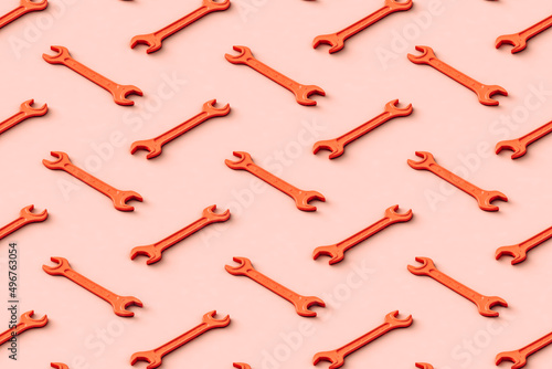 Three dimensional pattern of rows of orange colored wrenches flat laid against beige background photo