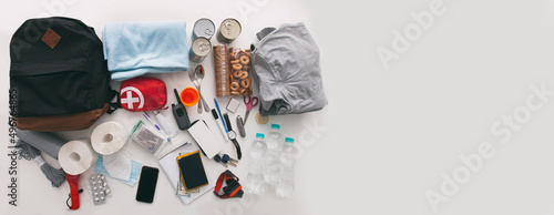 Emergency backpack equipment organized on the table. Documents, water,food, first aid kit and another items needed to survive. photo