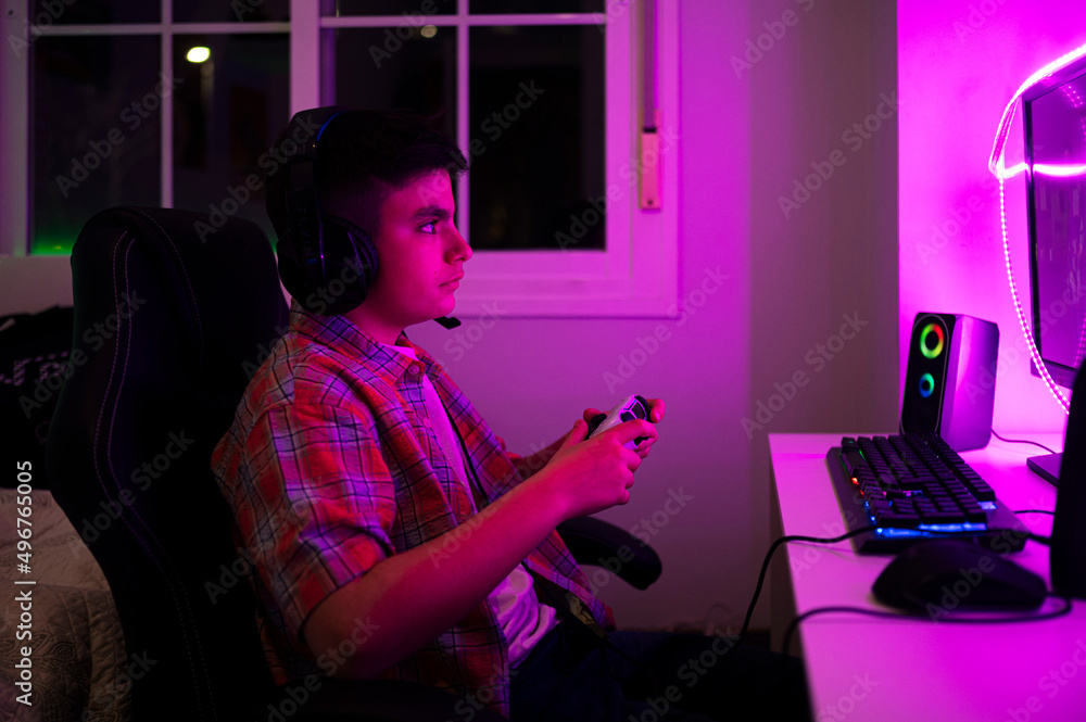 Boy with game controller sitting on chair in bedroom at home Boy with game controller sitting on chair in bedroom at home