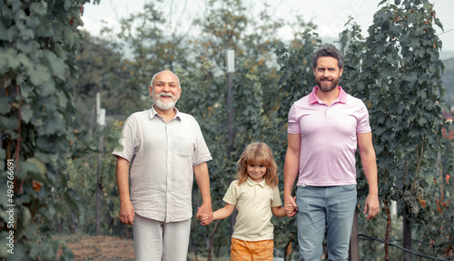Three generations of caucasian men. Boy child with father and old grandfather. Farmer men farming and gardening on farm oncountryside.
